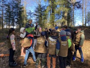Bild 2 – Klasse 2b im winterlichen Wald Zweitklässler der Naturpark-Grundschule Dobel stehen im Wald im Kreis und besprechen mit einer Waldpädagogin das Leben der Tiere im Winter.